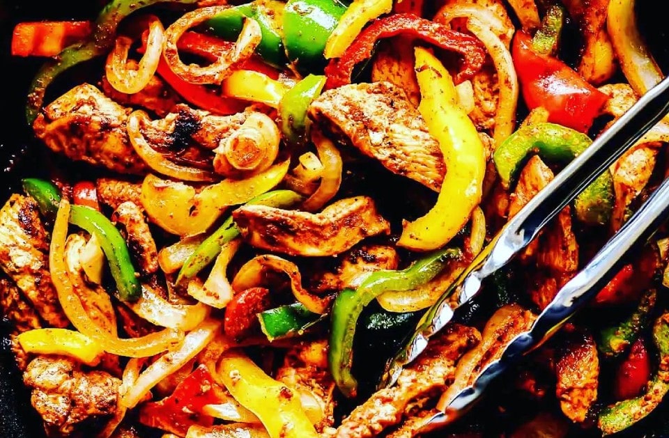Sizzling steak and chicken fajitas with peppers and onions